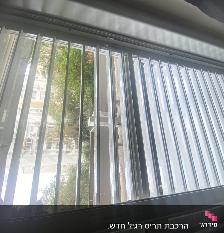 תריסים לבנים אנכיים פתוחים עם אור שמש חודר